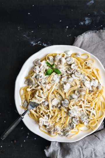 pasta spaghetti with creamy mushroom sauce and basil in white ceramic plate over old grunge dark table