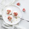 small strawberry and pistachio pavlova meringue cakes with mascarpone cream, fresh mint over white backdrop