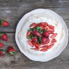 rustic pavlova cake with fresh strawberries and whipped cream ov