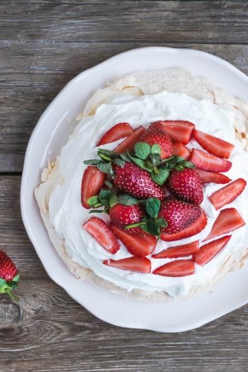 rustic pavlova cake with fresh strawberries and whipped cream ov