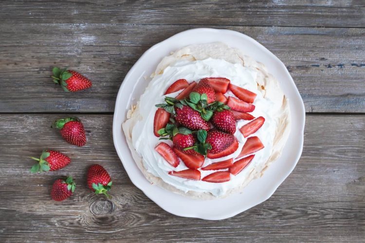 rustic pavlova cake with fresh strawberries and whipped cream ov