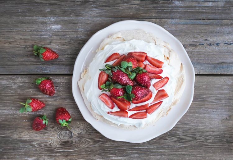 rustic pavlova cake with fresh strawberries and whipped cream ov