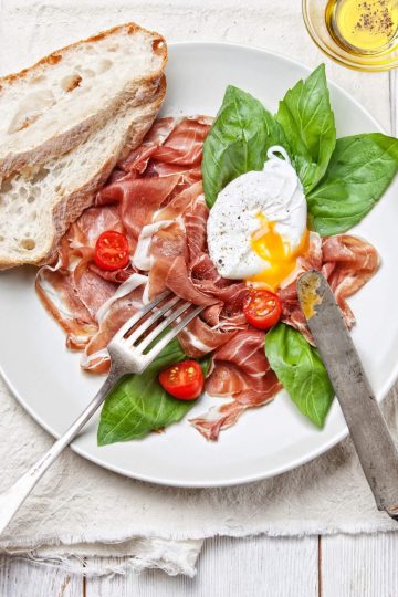 ham salad with poached egg on white wooden background