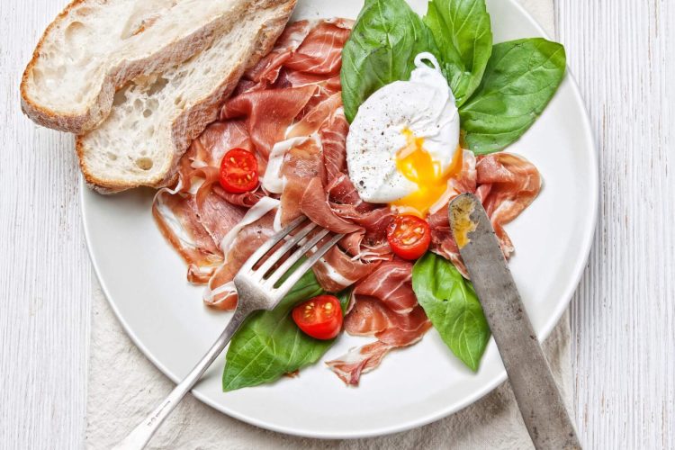 ham salad with poached egg on white wooden background