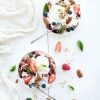healthy breakfast. berry crumble with fresh blueberries, raspberries, strawberries, almond, walnuts, pecans, yogurt, and mint in ceramic plates over white wooden surface